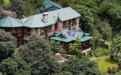 Exterior view of a large, luxurious cottage building surrounded by lush greenery